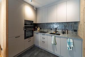 a kitchen with white cabinets and a sink at La Parenthèse du Goûter - by Care Concierge in Les Houches