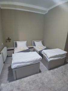 two beds in a room with white sheets at Xonobod НОТЕL in Khiva +26 photos