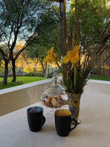 a table with two cups and a vase with flowers at Bridge View Hopetown in Hopetown