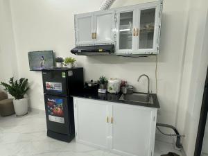 a kitchen with white cabinets and a black refrigerator at Harmony Apartment in Hanoi