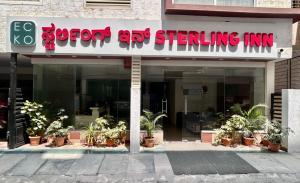 a sign for a store with potted plants in front of it at ECKO Sterling Inn Near Bangalore International Airport in Bangalore
