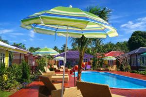 a pool with chairs and an umbrella next to a resort at Phetmanee Resort in Ko Yao Noi