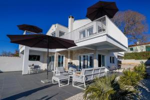 a white house with a patio with chairs and umbrellas at Casa Belladonna by Briskva in Višnjan