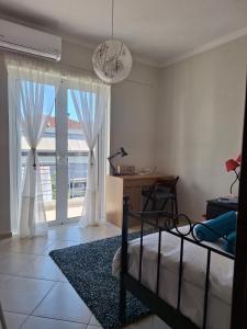a bedroom with a bed and a desk and windows at Dimitra's APARTMENT NAFPLIO in Nafplio
