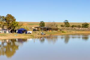 a group of tents next to a body of water at Bietjiedam's Campsites in Caledon
