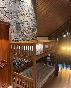 a wooden bunk bed in a room with a stone wall at The Pebble Shack in Idukki