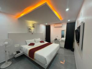 a bedroom with a large white bed and a tv at Tazinn in Wayanad
