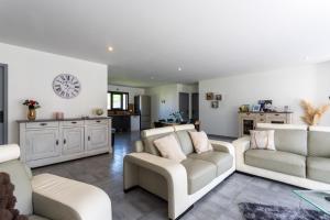 a living room with two couches and a clock on the wall at Maison Lahourcade in Lahourcade