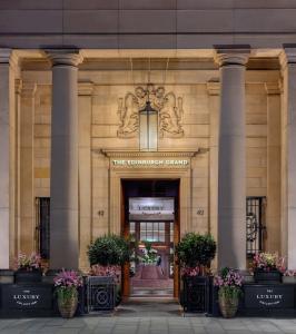 an entrance to a building with pillars and flowers at The Edinburgh Grand, a Luxury Collection Hotel, Edinburgh in Edinburgh