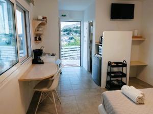 a room with a desk and a kitchen with a window at Filia Bungalow in Archangelos