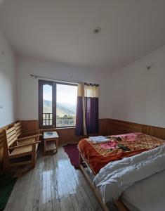 a bedroom with a bed and a window and a desk at Adventure valley Rajgundha in Kangra