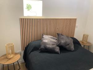 a bed with three pillows on it with two tables at Gîte du Banissou Chez Papy in Rosis