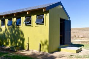 a small yellow building with windows and a door at Bietjiedam's Campsites in Caledon