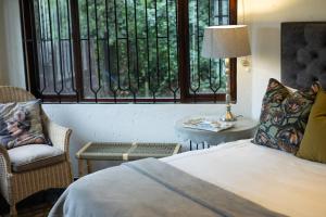 a bedroom with a bed and a chair and a window at The River Cottage in Muldersdrift