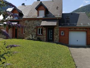 a stone house with a garage and a lawn at Chalet lac Celinda in Saint-Mamet