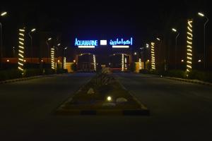 eine leere Straße in der Nacht mit einem Gebäude mit Neonschildern in der Unterkunft Aquamarine Kuwait Resort(Families Only) in Al Nuwaiseeb