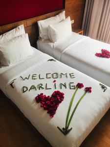 two beds with red flowers on them with the words welcome dancing at The Kirana Canggu Hotel in Canggu