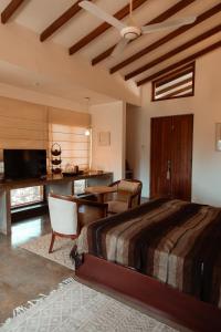 a bedroom with a bed and a desk and a table at Saffron & Blue in Bentota