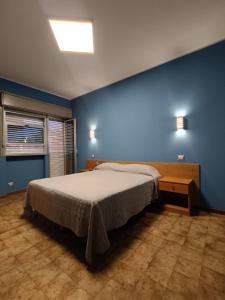 ein Schlafzimmer mit einem Bett und einer blauen Wand in der Unterkunft Hotel Il Dollaro in Villa San Giovanni