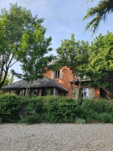 a red brick house with trees in front of it at Gîte La Tour du Moulin in Saint-Étienne-de-Montluc