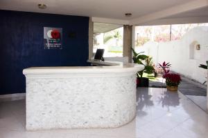 eine weiße Theke in einer Lobby mit einer Thekenplatte in der Unterkunft Capital O Hotel Partidor Del Sol, Oaxtepec in Oaxtepec