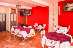 ein Restaurant mit roten Wänden und weißen Tischen und Stühlen in der Unterkunft Capital O Hotel Partidor Del Sol, Oaxtepec in Oaxtepec