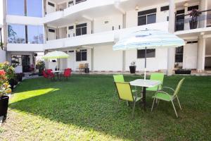 ein Tisch und Stühle mit einem Sonnenschirm im Garten in der Unterkunft Capital O Hotel Partidor Del Sol, Oaxtepec in Oaxtepec