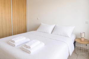 a white bed with two towels on top of it at Appartement Terrasse St Florent in Saint-Florent
