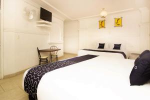 ein Hotelzimmer mit zwei Betten und einem Tisch in der Unterkunft Capital O Hotel Partidor Del Sol, Oaxtepec in Oaxtepec + 52 Fotos
