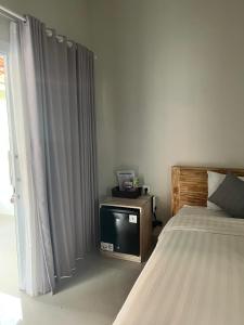 a bedroom with a bed and a tv next to a window at D'A HOUSE in Amed