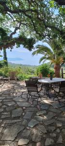 a table and a bench on a stone patio at Wellanidia Cottage Skoutari in Gythio