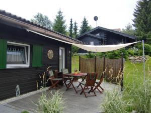 eine Terrasse mit einem Tisch und Stühlen neben einem Haus in der Unterkunft Ferienhaus Altenstrasser in Philippsreut