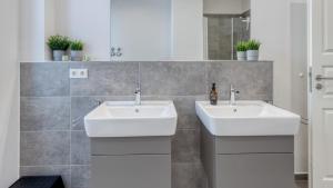 two white sinks in a bathroom with tiles at Sali Homes - Opera Loge 2BR Balcony in Bayreuth +12 photos