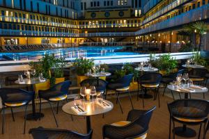 a restaurant with a pool and tables and chairs at Molitor Hotel & Spa Paris - MGallery Collection in Paris