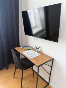 a desk with a chair and a television on a wall at Sali Homes - Opera Loge 2BR Balcony in Bayreuth