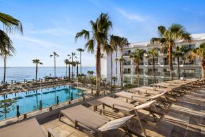 a hotel with a pool and chairs and palm trees at Hotel Riu Palace Nautilus - Adults Only in Torremolinos