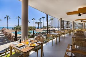 a restaurant with tables and chairs with a view of the ocean at Hotel Riu Palace Nautilus - Adults Only in Torremolinos