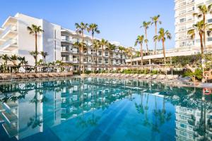 a swimming pool in front of a hotel with palm trees at Hotel Riu Palace Nautilus - Adults Only in Torremolinos