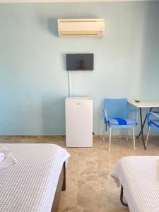 a room with two beds and a tv and a table and chairs at Emir Palas Hotel in Ekincik