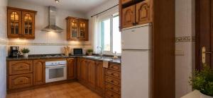 a kitchen with wooden cabinets and a white refrigerator at Chalet con jardin cerca de la playa in Can Pastilla