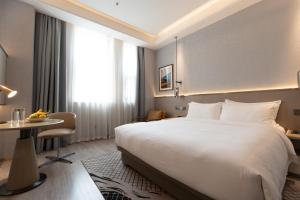 a hotel room with a large bed and a table at JOY Hotel Hangzhou in Hangzhou +33 photos