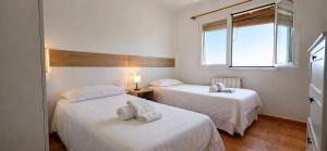 two beds in a small room with a window at Chalet con jardin cerca de la playa in Can Pastilla