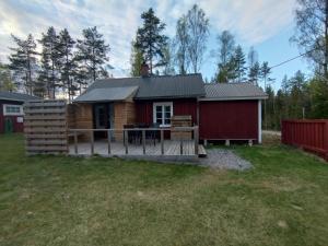 a small cabin with a deck in a yard at Rosa's stuga in Tasebo