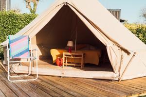 a tent with a bed and a chair on a wooden deck at Glamping Spot - Penmarch in Penmarch