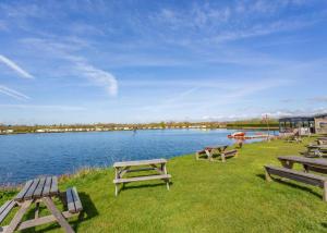 a group of picnic tables on the grass near a lake at Croft Farm Water Park in Tewkesbury