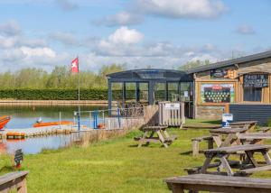 a building with picnic tables next to a river at Croft Farm Water Park in Tewkesbury