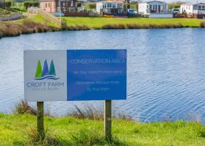 a sign in the grass next to a body of water at Croft Farm Water Park in Tewkesbury +63 photos