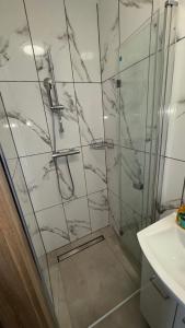 a shower with a glass door next to a sink at Apartament 1 Słoneczna in Ełk +5 photos