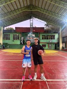 two men are standing on a tennis court at VAL Homestay in Siquijor