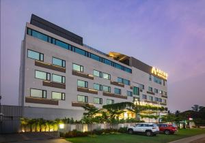 a building with cars parked in front of it at Arcor Hotels Mysuru in Mysore